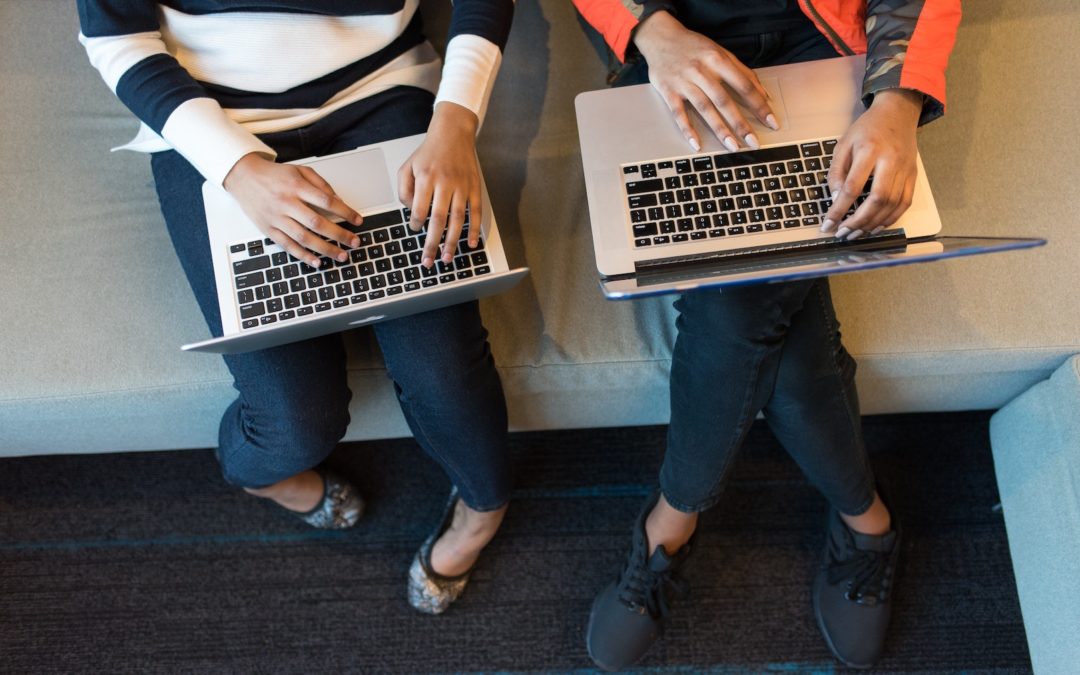 two people on laptops comparing playlists for music for business